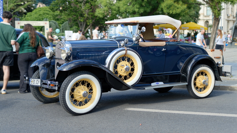 A 1931 Ford Model A DeLuxe Roadster featuring a navy blue exterior and yellow wire wheels